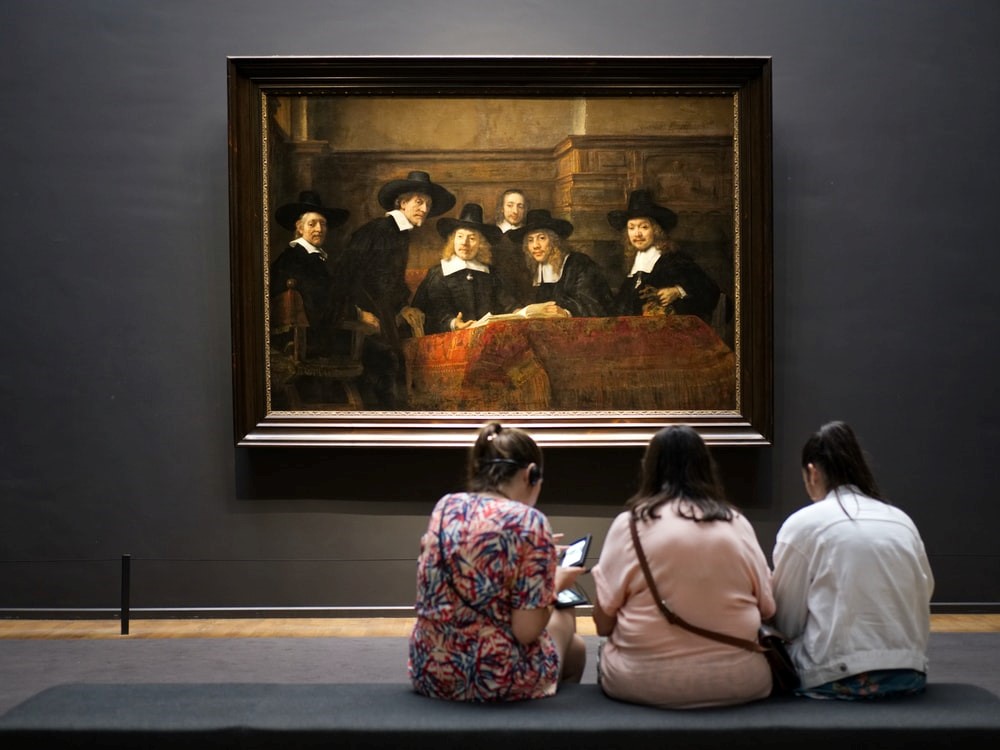 three women look at painting on wall